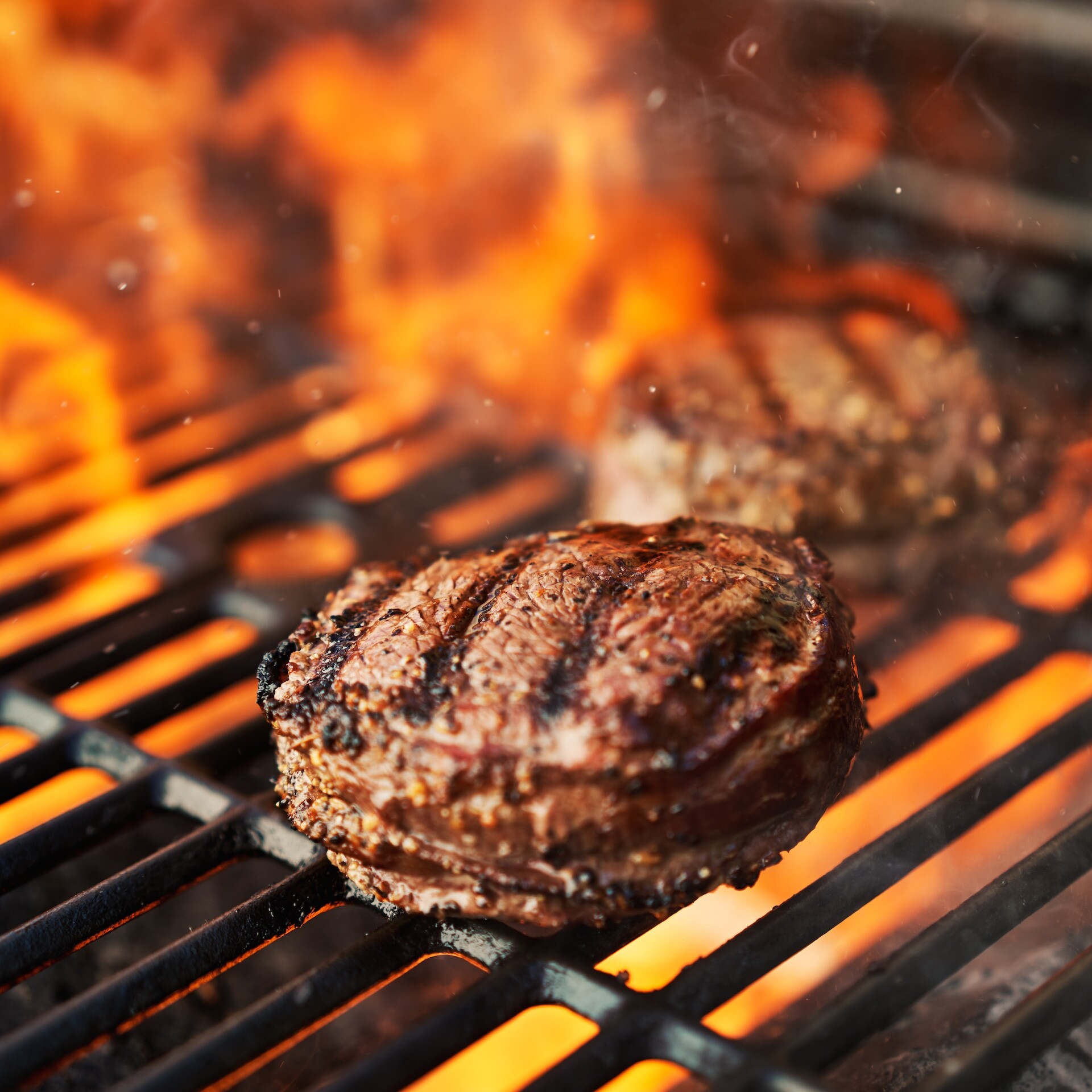 grilling filet mignon steaks on grill with flames